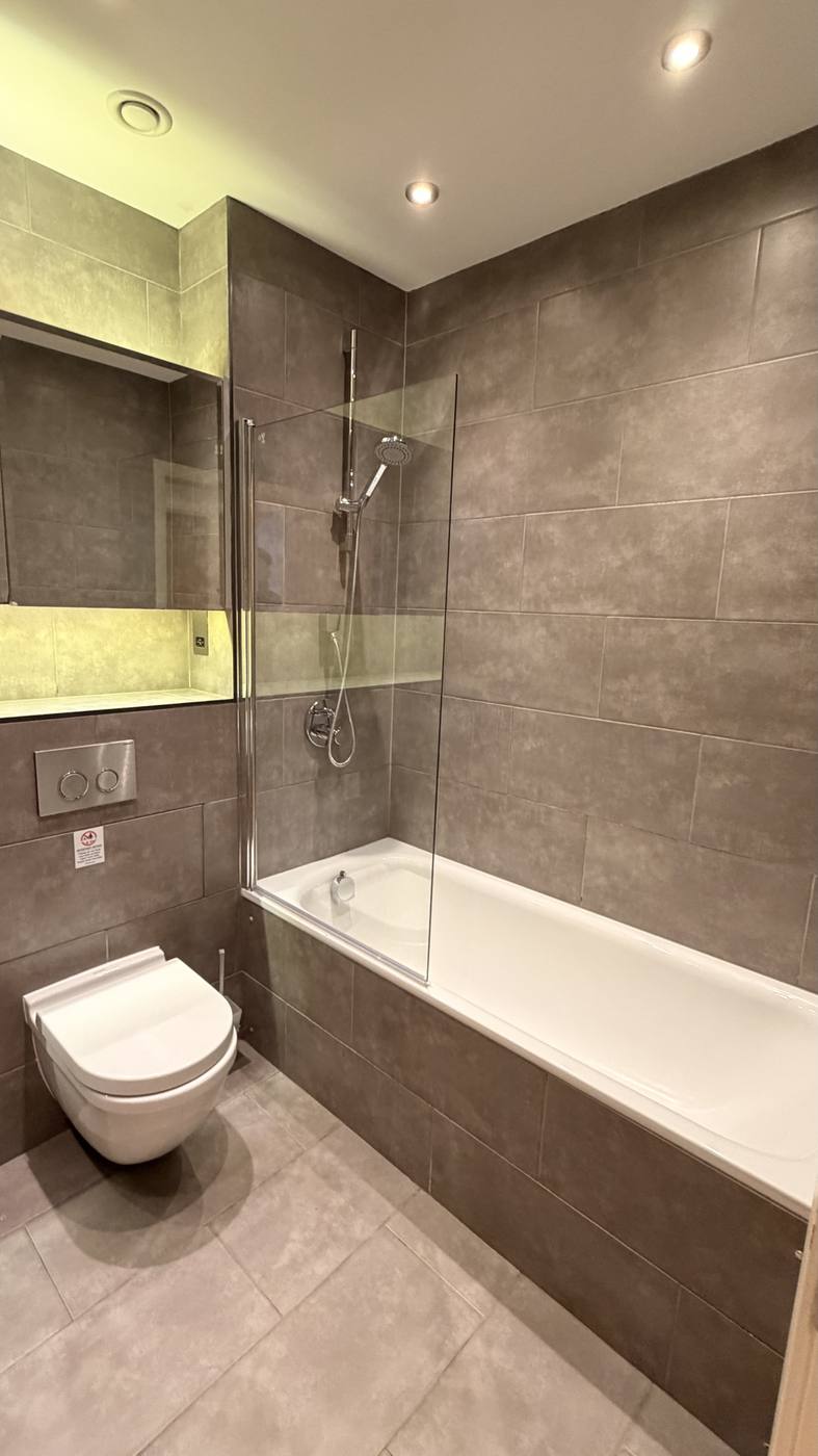 Refurbished bathroom with large-format tiles and lit niche